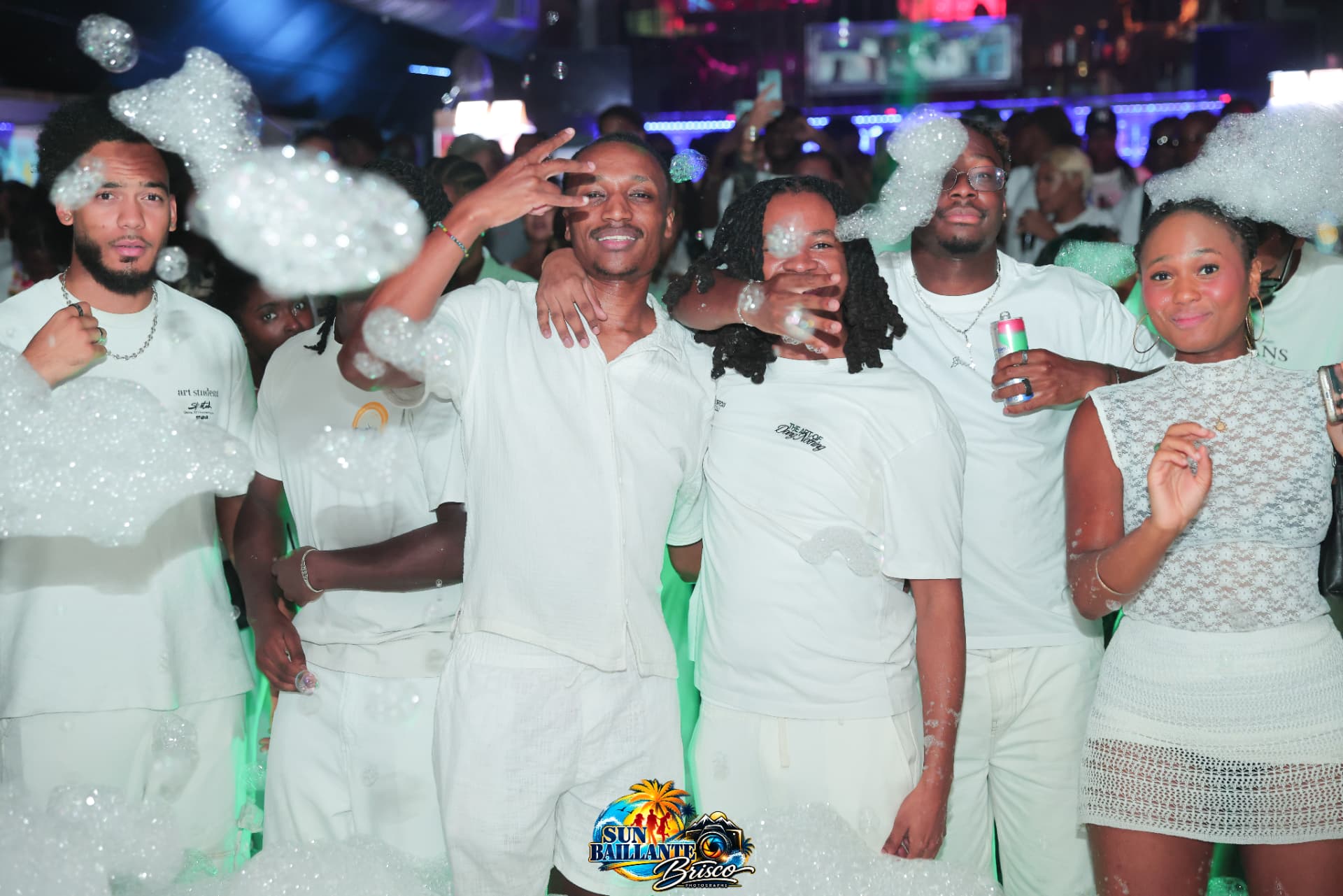 Groupe d'amis en blanc au milieu de la mousse d'une soirée Sun Bailante