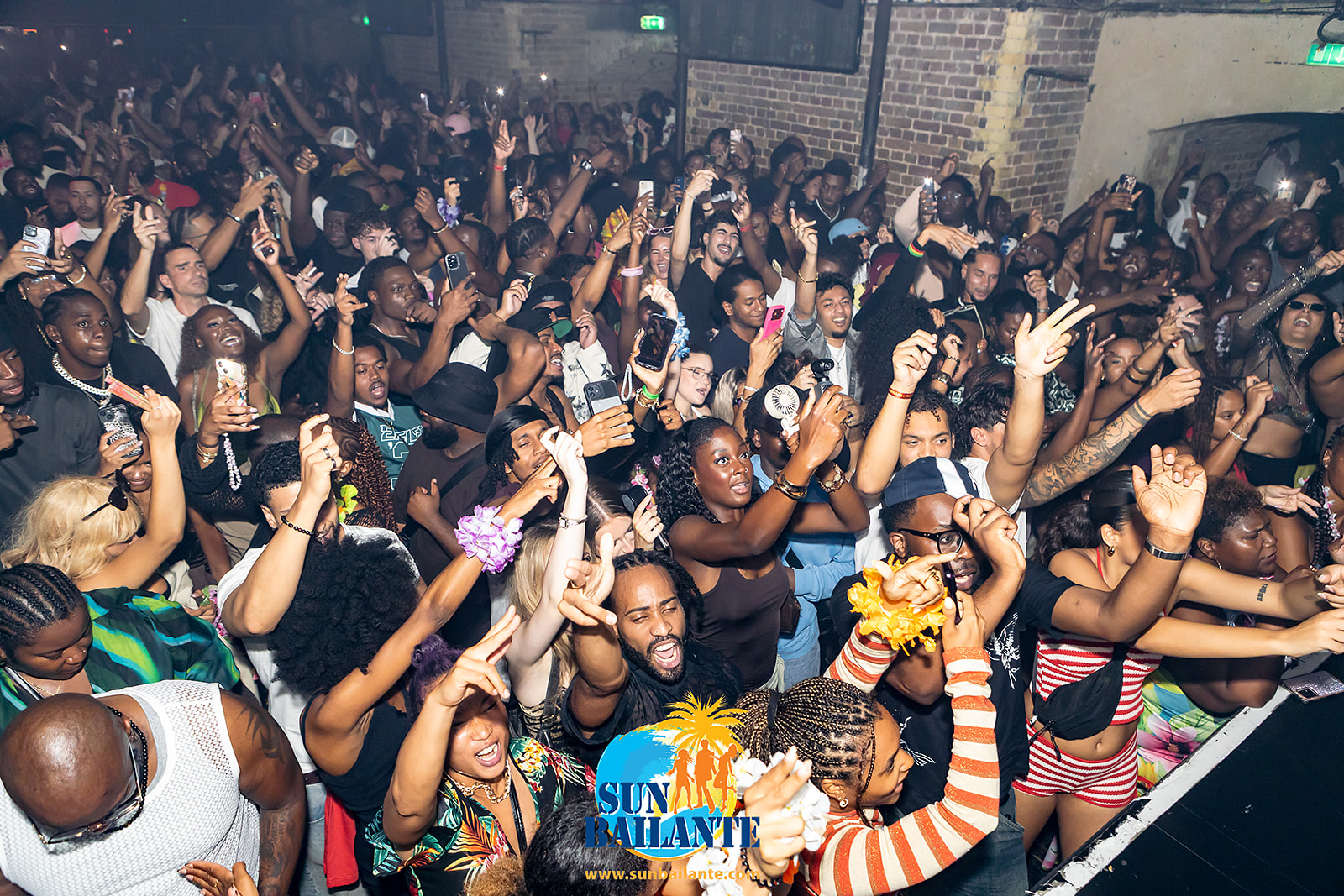 Public souriant, bracelets et fleurs tropicales, soirée Sun Bailante